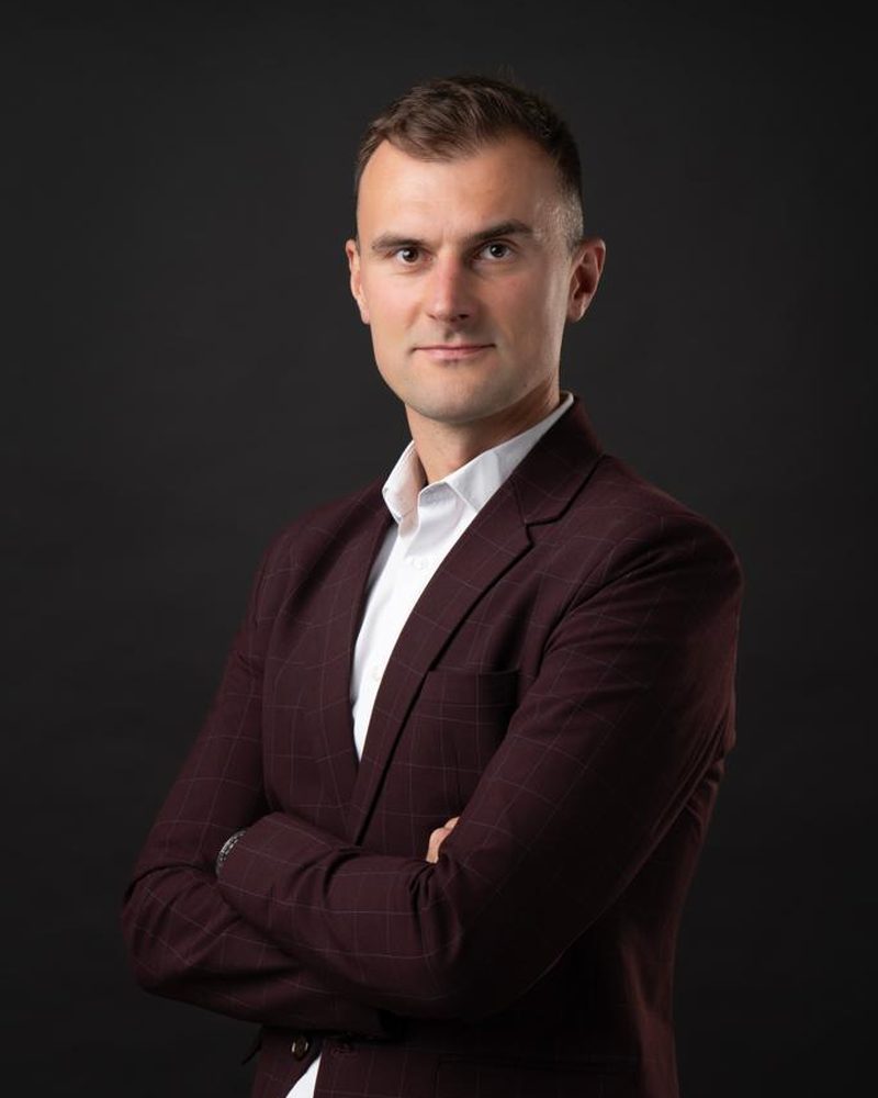 Michal Ondrej in a burgundy suit, arms crossed